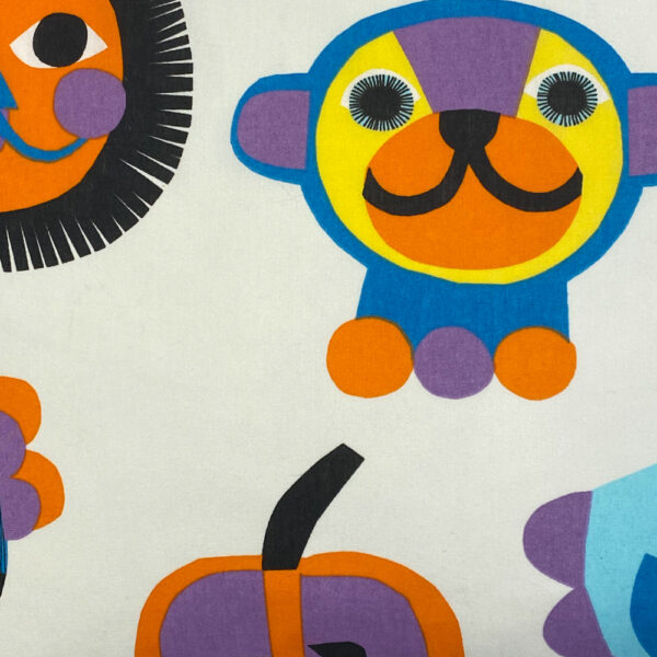 Detailbildweißer Vintagepolster mit ca 15 Zentimeter großen stilisierten einzelnen Tierfiguren, Sonnen und Früchten in Knallblau, Orange, Lila, Gelb, Dunkelblau und Schwarz bedruckt