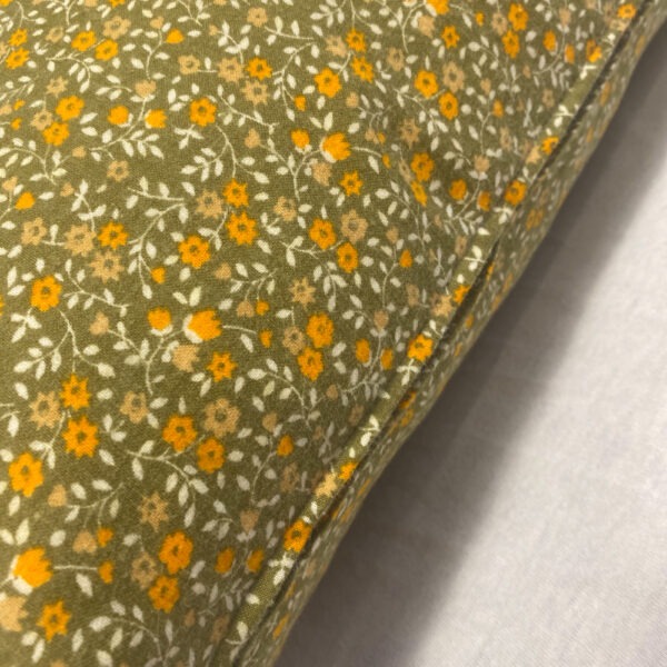 Seitenansicht mit Reißverschluss hell- moosgrünfarbenes Vintage-Kissen mit aufgedruckten kleinen Streublümchen in Orange und weißen Stielen