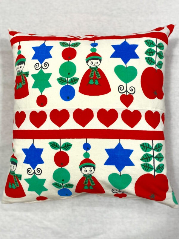 Weißes Sofakissen mit aufgedruckten weihnachtlichen Motiven, in Reihen angeordnete Herzen, alternierende Äpfel, Stene und Herzen und stilisierte Bubenfiguren in Rot, Mint,Blau und Schwarz.