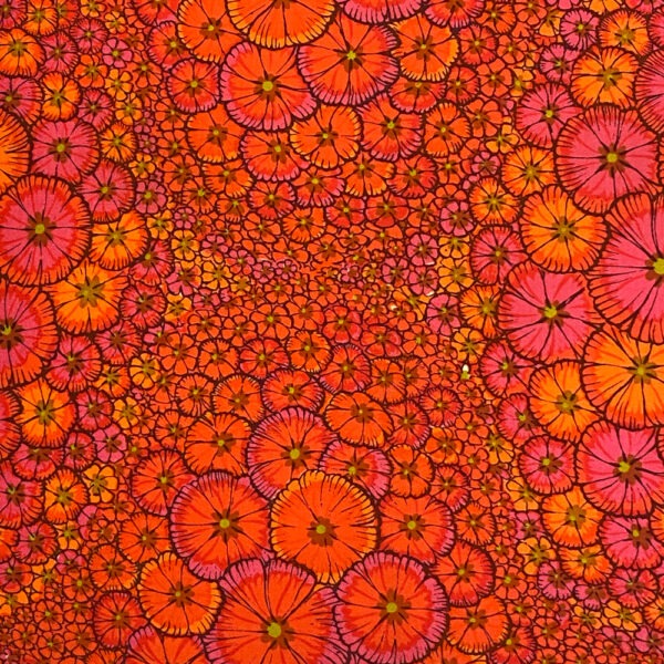 Detail Vintage-Polster aus leuchtend rotem Baumwollstoff flächendeckend bedruckt mit kleinen Blüten in allen rot, pink und orangen Schattierungen mit hellgrünem Blütenstempel