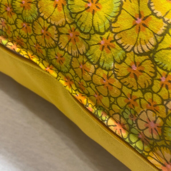 Seitenansicht mit Reißverschluss Vintage-Polster aus leuchtend gelbem Baumwollstoff flächendeckend bedruckt mit kleinen Blüten in allen gelb und grün Schattierungen mit orangem Blütenstempel